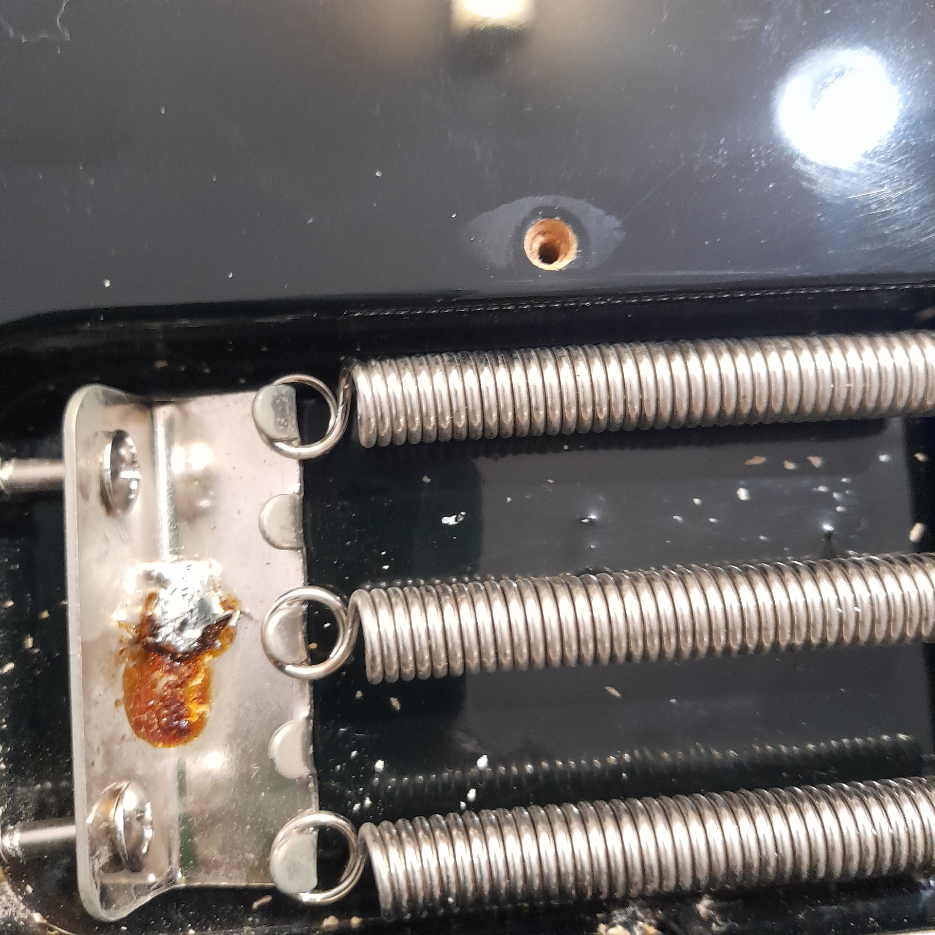 Tremolo spring cavity before repair showing corroded solder joint and damaged ground wire on the claw